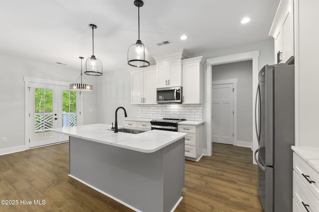 kitchen with a sink, stainless steel appliances, tasteful backsplash, white cabinetry, and dark wood-style floors