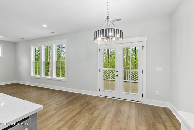 unfurnished dining area with healthy amount of natural light, baseboards, wood finished floors, and recessed lighting