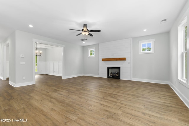 unfurnished living room featuring a chandelier, a fireplace, wood finished floors, a ceiling fan, and recessed lighting