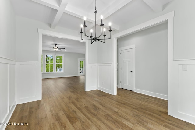unfurnished dining area with beam ceiling, a decorative wall, a chandelier, wood finished floors, and wainscoting