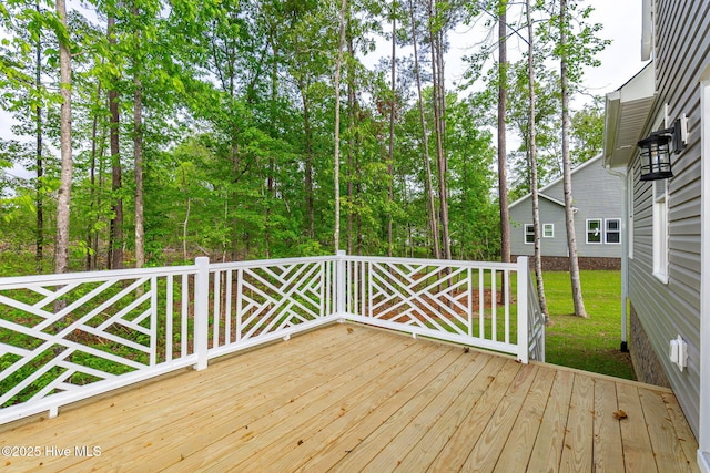 deck featuring view of wooded area and a yard