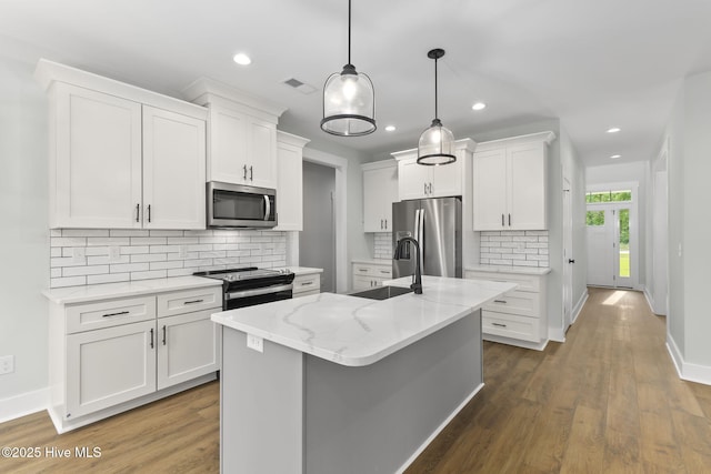 kitchen featuring appliances with stainless steel finishes, a sink, white cabinetry, backsplash, and pendant lighting