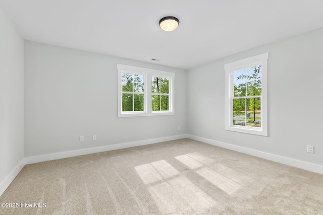 unfurnished room featuring healthy amount of natural light, carpet floors, and baseboards