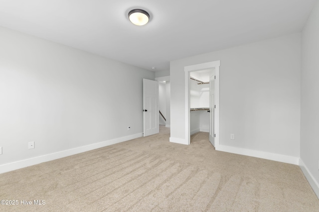 unfurnished bedroom featuring carpet floors, baseboards, and a walk in closet