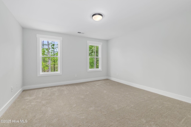 carpeted spare room with plenty of natural light and baseboards
