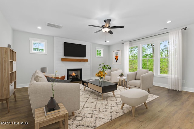 living area with a large fireplace, baseboards, recessed lighting, and wood finished floors