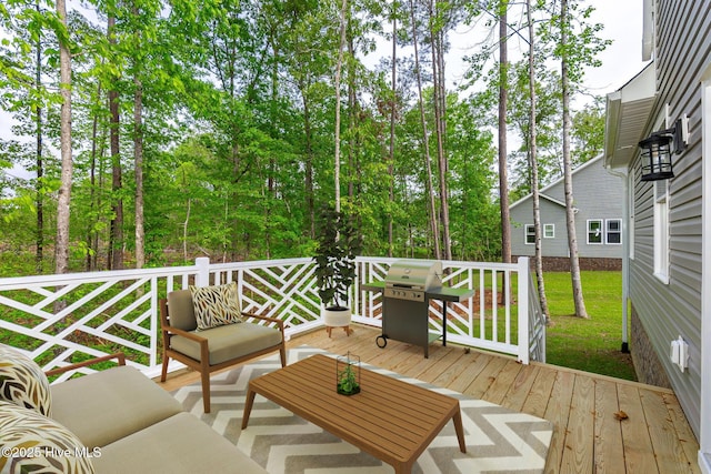 wooden terrace with an outdoor hangout area, grilling area, and view of wooded area