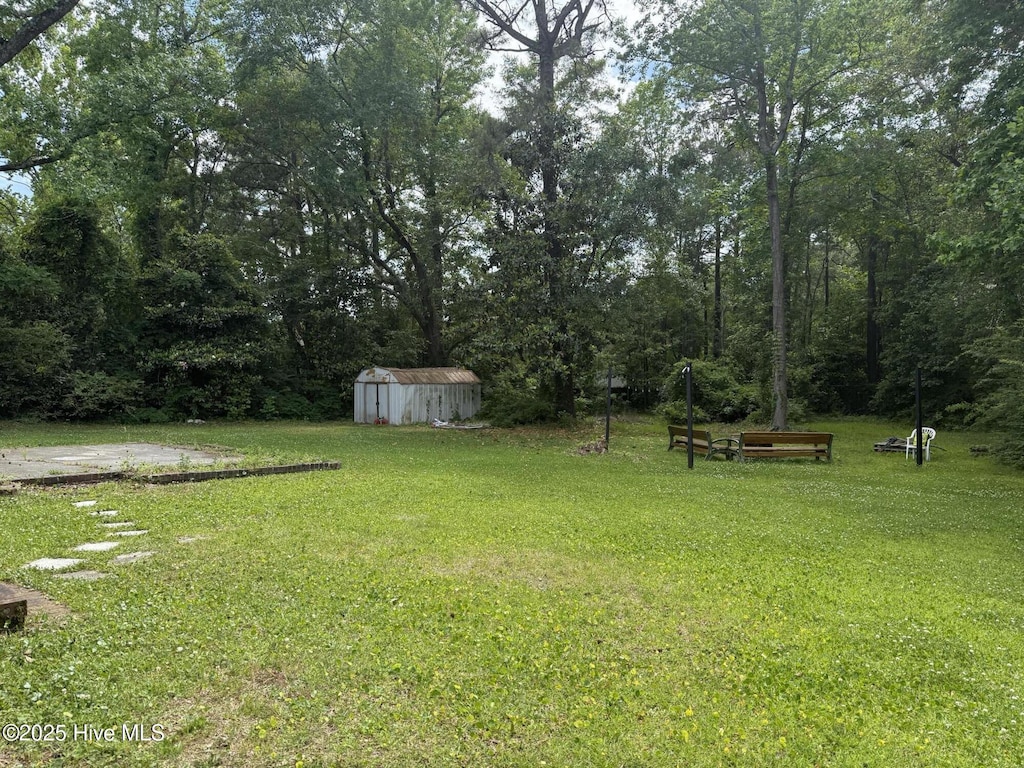 view of green lawn featuring a storage unit and an outbuilding