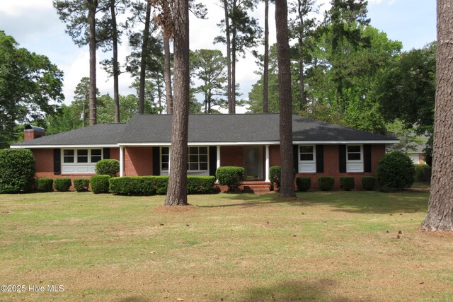 ranch-style home featuring brick siding, a front yard, and a chimney