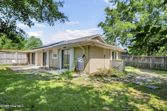 7404 Countywood Way, Wilmington, NC 28411 - rear view of house with stucco siding, a patio, and roof mounted solar panels