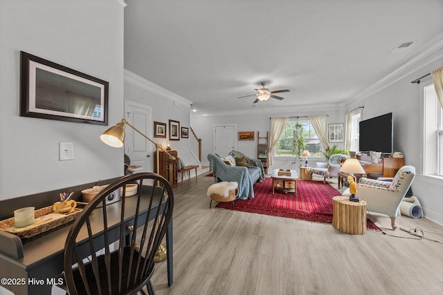 living area with wood finished floors, a ceiling fan, stairway, crown molding, and baseboards