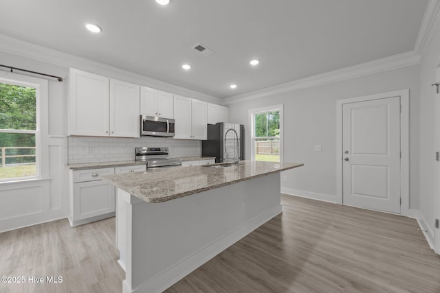 104 Two Sisters Ter, Sneads Ferry, NC 28460 - kitchen with appliances with stainless steel finishes, ornamental molding, a kitchen island with sink, light wood-type flooring, and white cabinetry