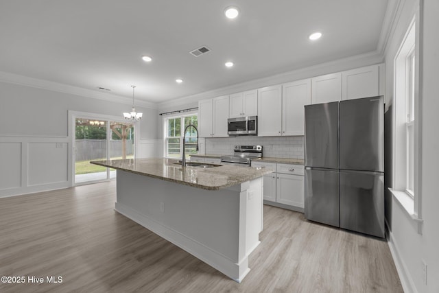 104 Two Sisters Ter, Sneads Ferry, NC 28460 - kitchen featuring stainless steel appliances, a sink, light stone counters, white cabinetry, and an island with sink