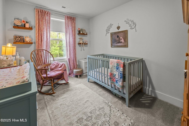 carpeted bedroom featuring a crib and baseboards