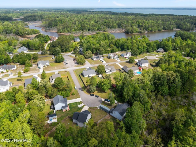 aerial view of property's location with a heavily wooded area, a nearby body of water, and nearby suburban area