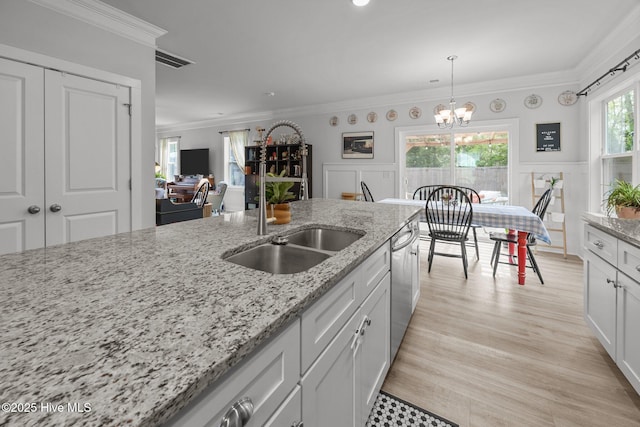 kitchen featuring a sink, a chandelier, ornamental molding, light stone countertops, and white cabinetry