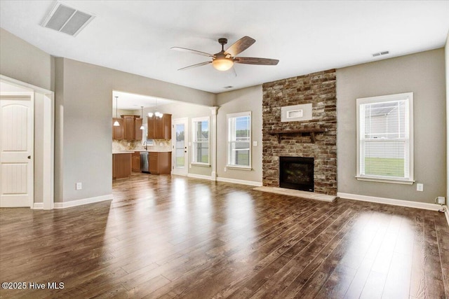 unfurnished living room with ceiling fan with notable chandelier, visible vents, and dark wood finished floors