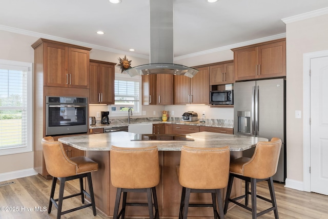 139 Sound Point Dr, Harkers Island, NC 28531 - kitchen with appliances with stainless steel finishes, island range hood, crown molding, light wood-style floors, and a kitchen breakfast bar