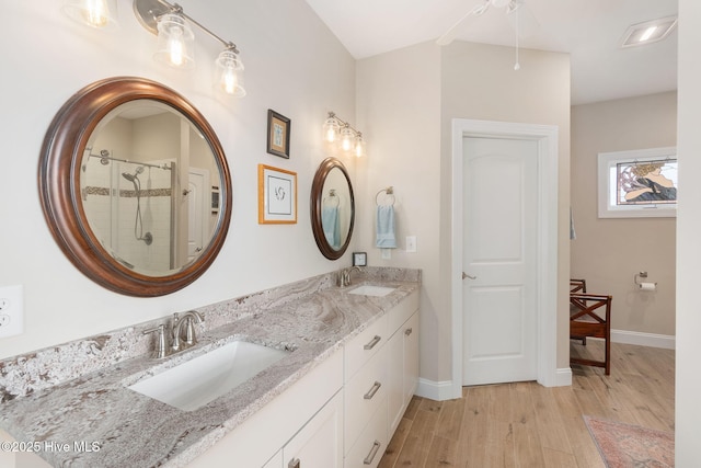 139 Sound Point Dr, Harkers Island, NC 28531 - bathroom with wood finished floors, double vanity, a shower stall, and baseboards