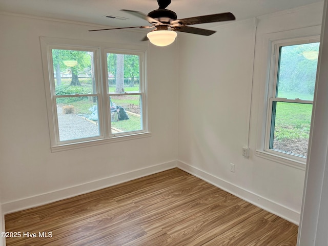 unfurnished room featuring a ceiling fan, baseboards, ornamental molding, visible vents, and light wood-type flooring