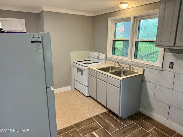 kitchen featuring crown molding, gray cabinetry, a sink, and white appliances
