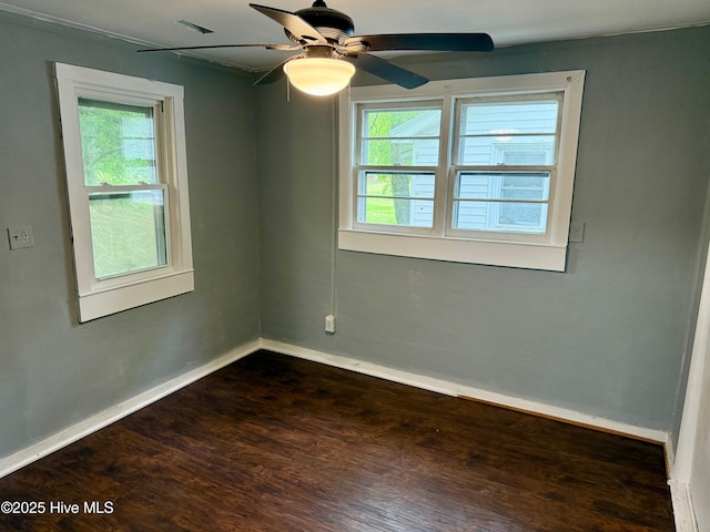 empty room featuring a ceiling fan, a wealth of natural light, baseboards, and dark wood finished floors