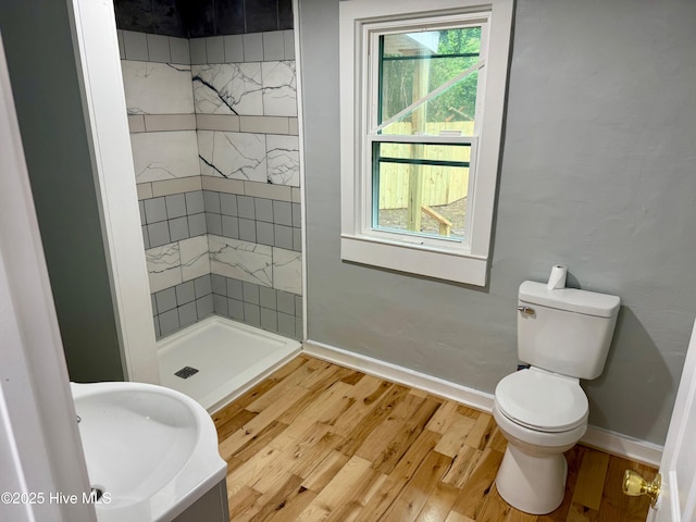bathroom with toilet, baseboards, wood finished floors, and a shower stall