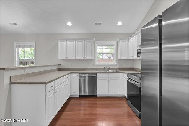 kitchen with stainless steel appliances, a sink, a peninsula, plenty of natural light, and recessed lighting