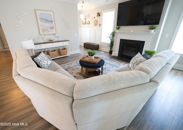 6959 Gracieuse Ln SW, Ocean Isle Beach, NC 28469 - living room featuring crown molding, a fireplace with flush hearth, wood finished floors, and a wainscoted wall