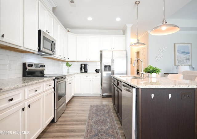 6959 Gracieuse Ln SW, Ocean Isle Beach, NC 28469 - kitchen featuring stainless steel appliances, a sink, ornamental molding, a center island with sink, and white cabinetry