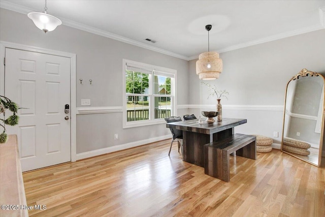 dining area with baseboards, light wood finished floors, crown molding, and visible vents
