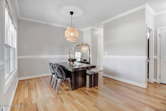 dining space featuring baseboards, ornamental molding, and light wood-type flooring