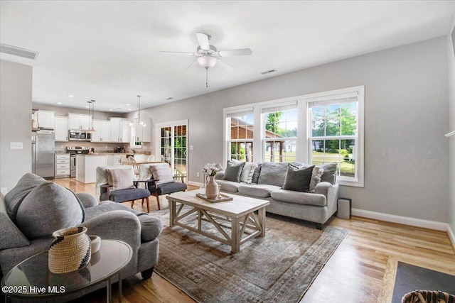 living area with ceiling fan, baseboards, light wood-type flooring, and visible vents
