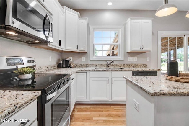 kitchen featuring a sink, light wood finished floors, white cabinetry, a wealth of natural light, and appliances with stainless steel finishes