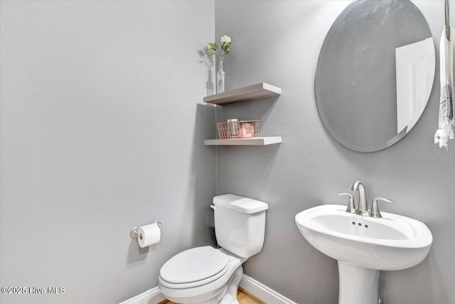half bath featuring a sink, toilet, and baseboards