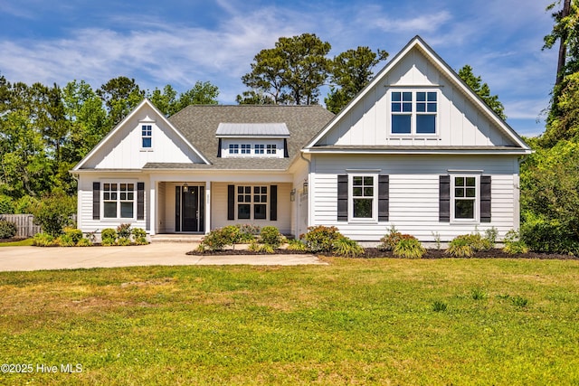 view of front of house with board and batten siding, a front yard, roof with shingles, and covered porch