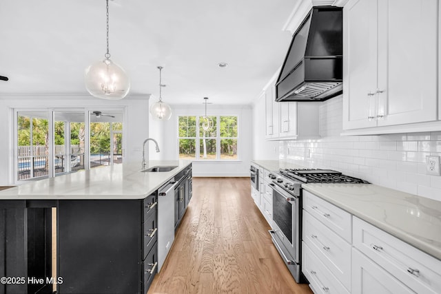 kitchen with appliances with stainless steel finishes, custom exhaust hood, a sink, light wood-style flooring, and white cabinets