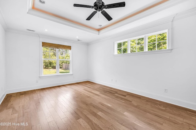 spare room featuring a tray ceiling, crown molding, baseboards, hardwood / wood-style flooring, and ceiling fan