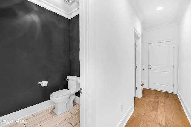 bathroom featuring ornamental molding, wood finished floors, toilet, and baseboards