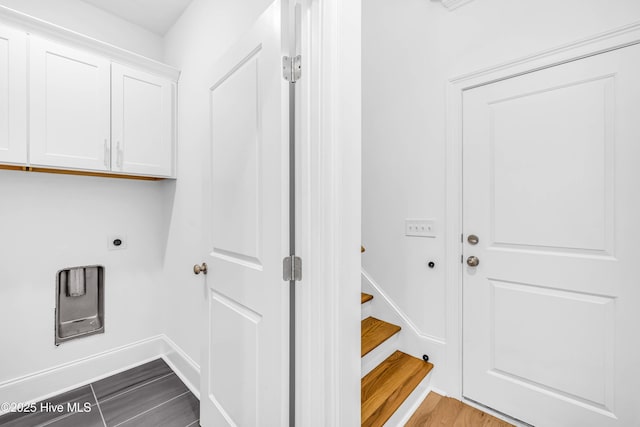 clothes washing area with cabinet space, electric dryer hookup, dark wood-type flooring, and baseboards