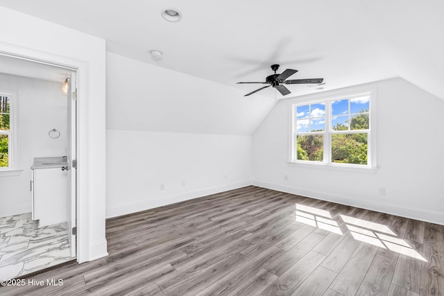 additional living space featuring vaulted ceiling, ceiling fan, wood finished floors, and baseboards