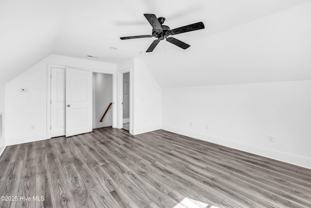 additional living space featuring vaulted ceiling, wood finished floors, a ceiling fan, and baseboards