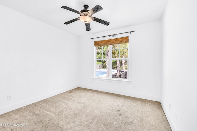 carpeted spare room with a ceiling fan and baseboards