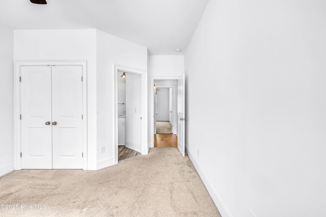 unfurnished bedroom with light carpet, a closet, and baseboards