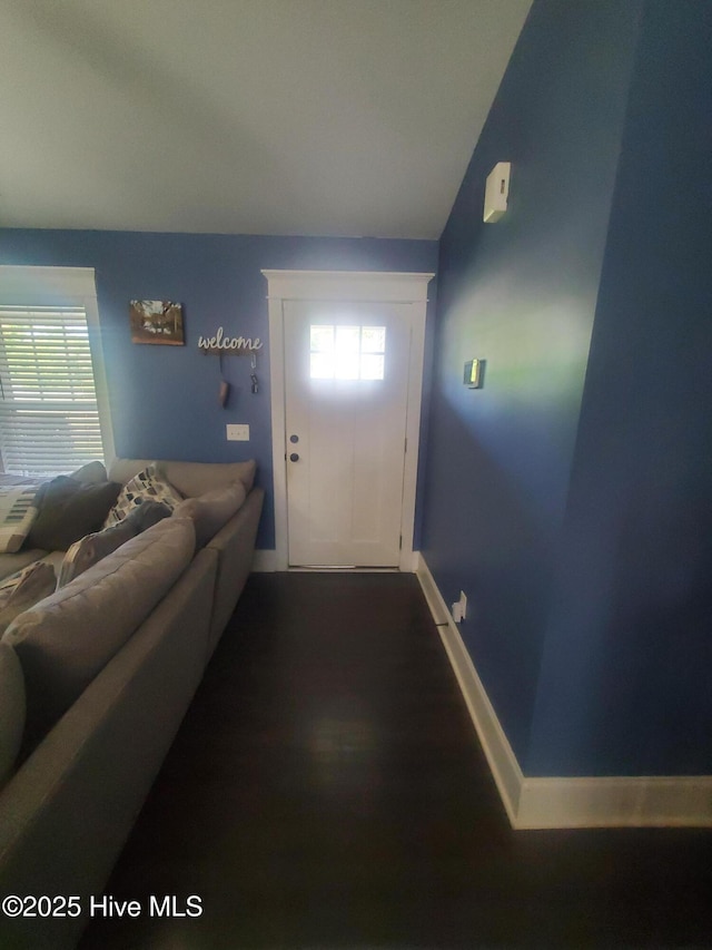 doorway to outside with baseboards, lofted ceiling, and wood finished floors