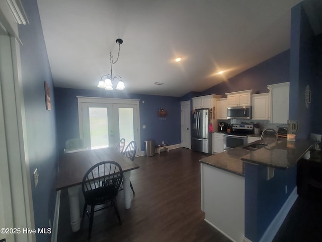 kitchen with appliances with stainless steel finishes, a sink, lofted ceiling, decorative backsplash, and white cabinets