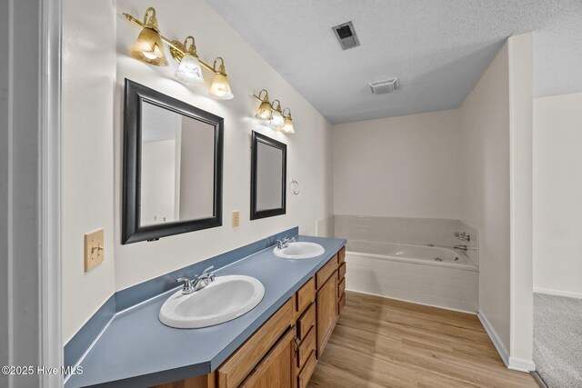 123 W Victoria Ct Unit F, Greenville, NC 27834 - full bath with a garden tub, wood finished floors, double vanity, a textured ceiling, and baseboards
