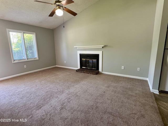 unfurnished living room with dark colored carpet, a ceiling fan, a textured ceiling, lofted ceiling, and a fireplace