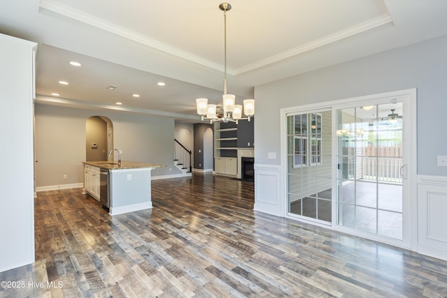 kitchen featuring arched walkways, dark wood-style flooring, open floor plan, a tray ceiling, and recessed lighting