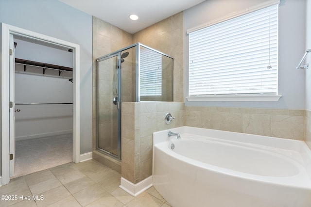 full bath featuring a stall shower, a spacious closet, a bath, and tile patterned flooring